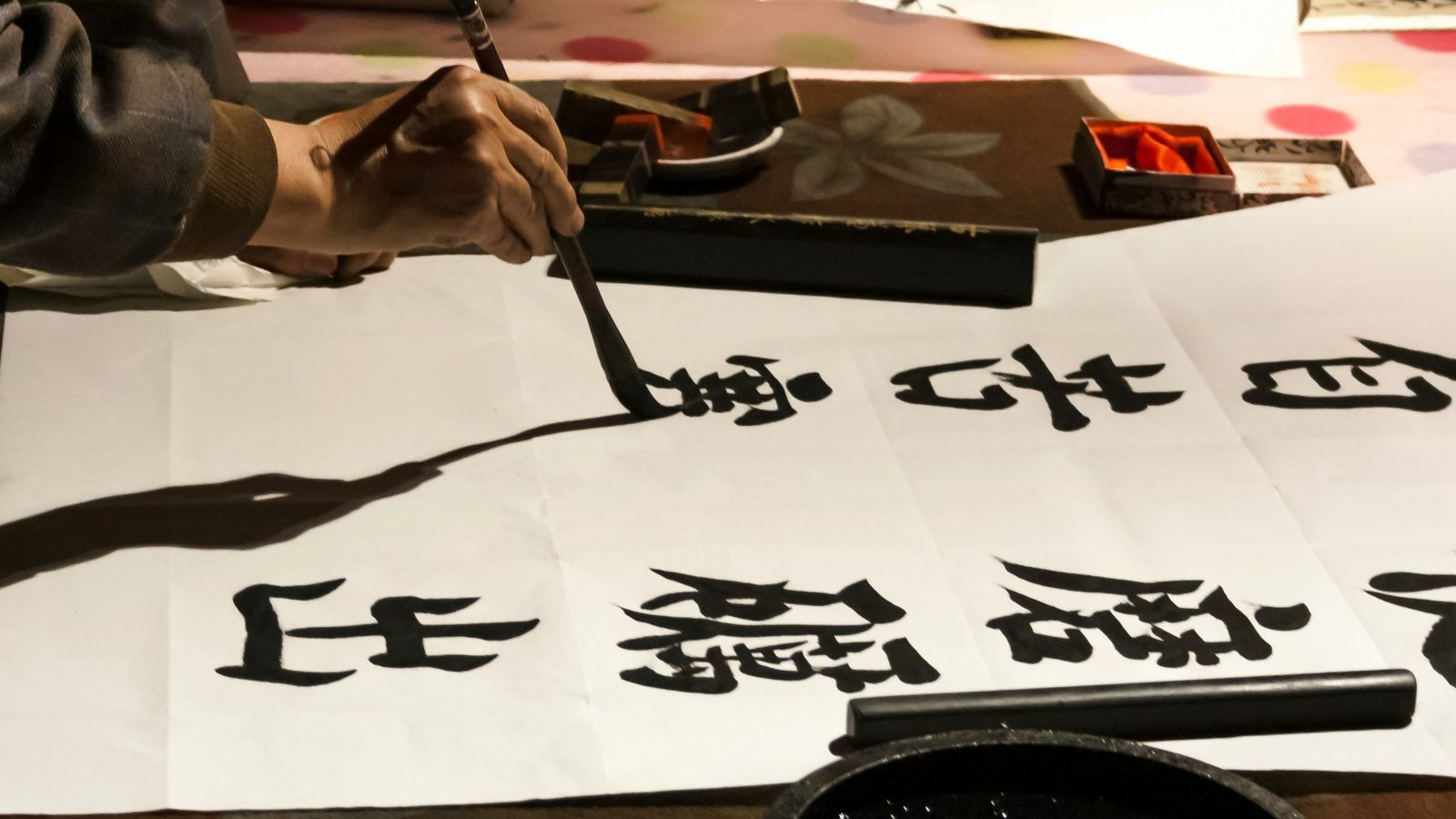 Une main écrivant des caractères chinois au pinceau sur du papier