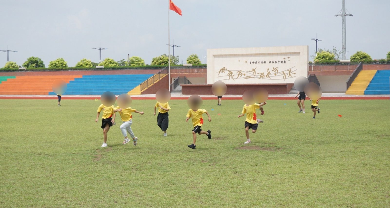 Des enfants en maillot de camp jaune courant sur un terrain de sport scolaire